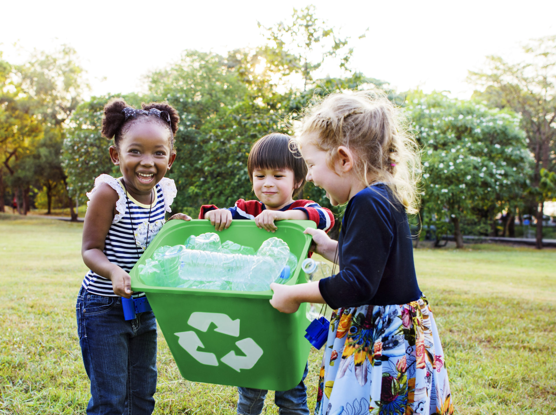 Young children holding a full recycling bin.