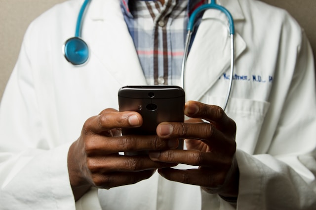 Person wearing lab coat holding a phone